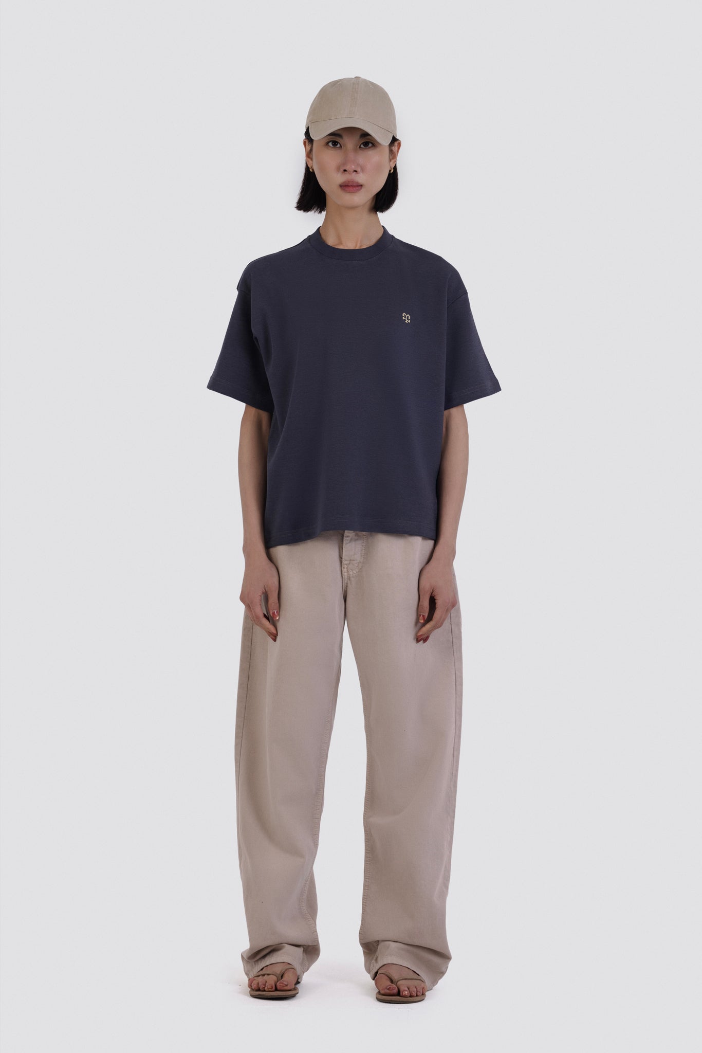 Person wearing a navy t-shirt and beige pants on a white background