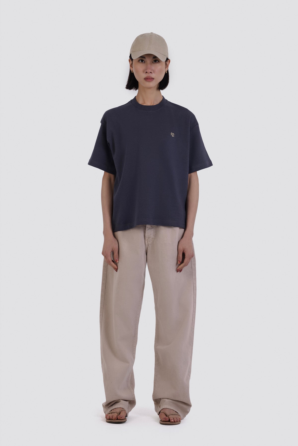 Person wearing a navy t-shirt and beige pants on a white background