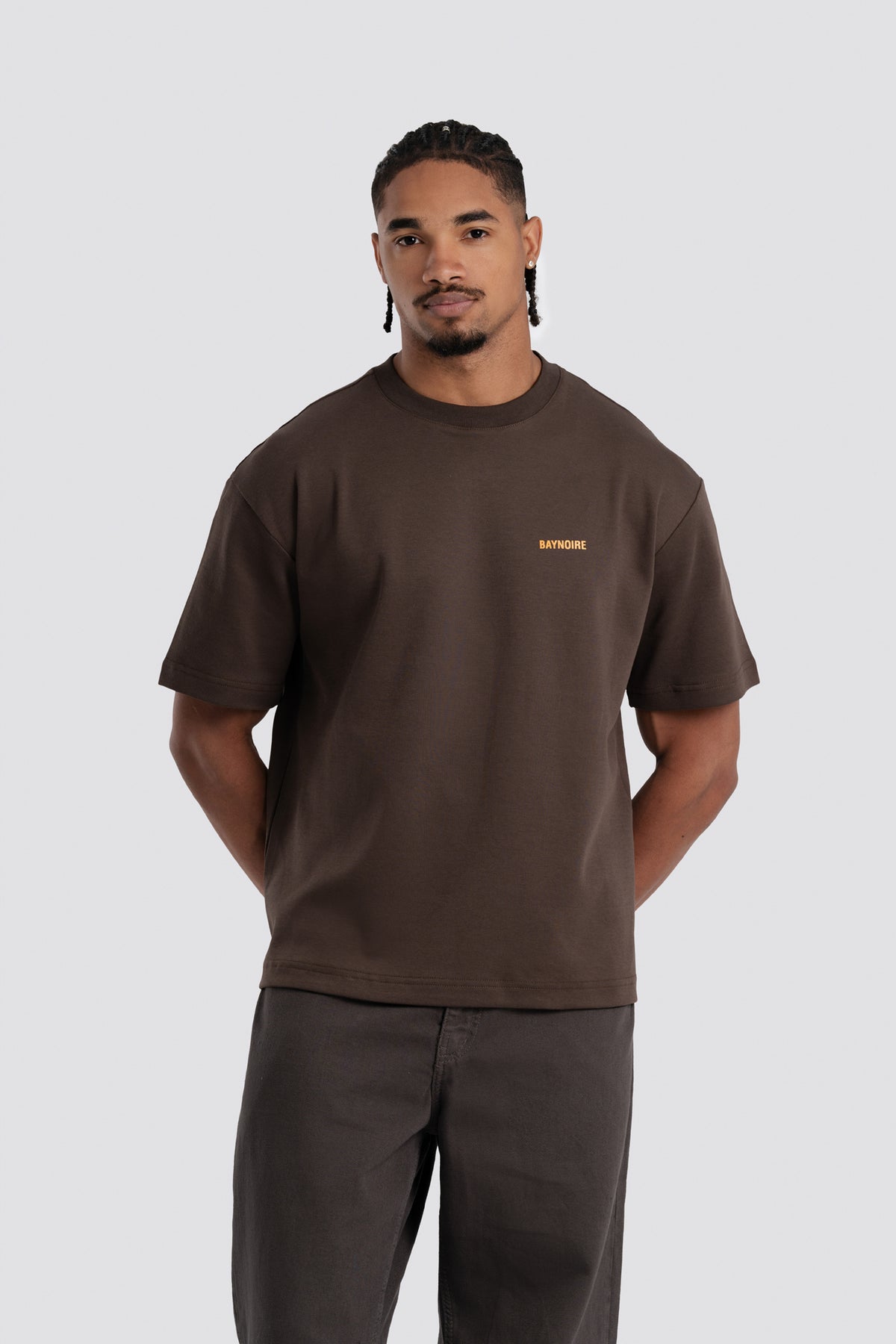 Man wearing a brown t-shirt with a logo on a white background