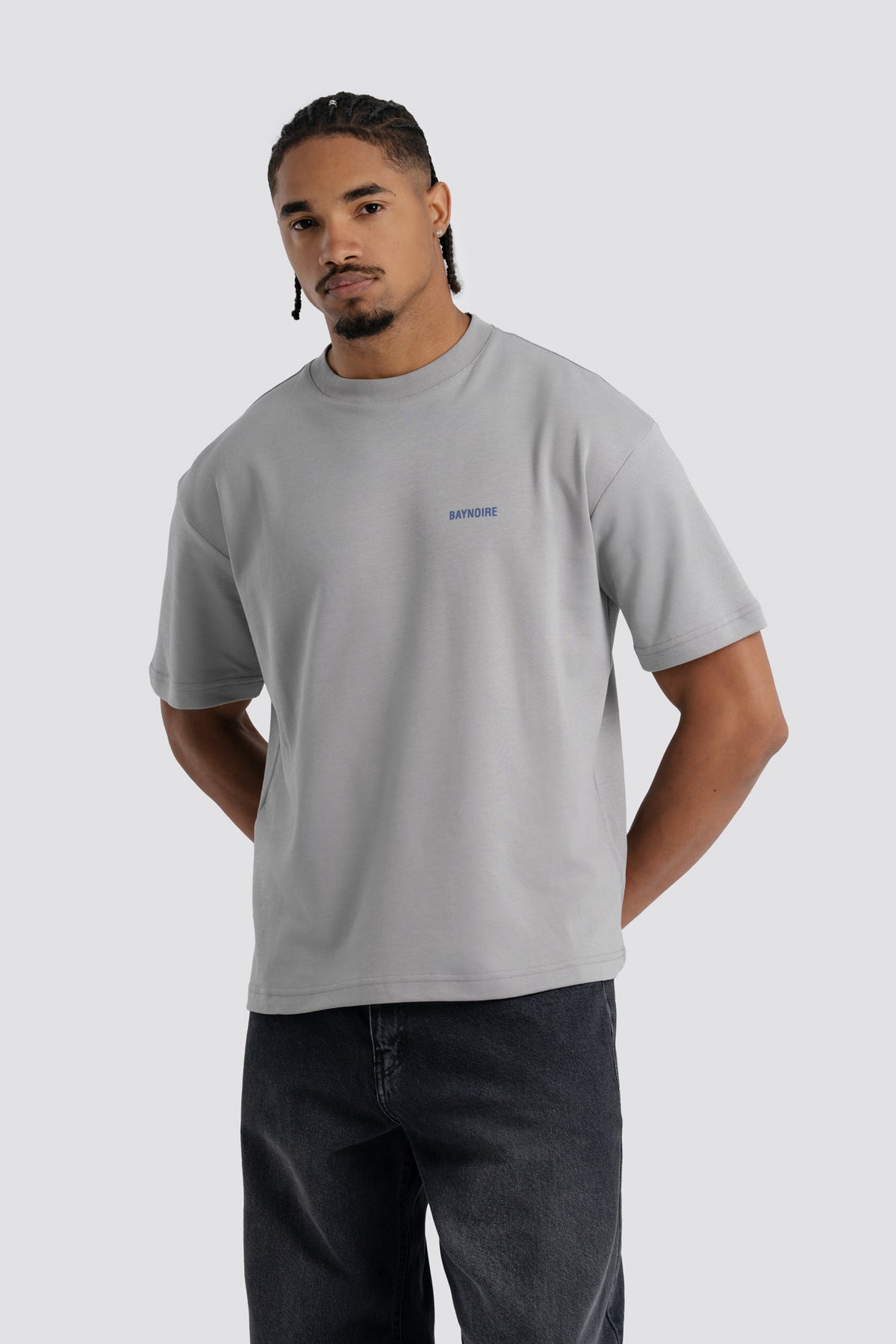 Man wearing a gray t-shirt with a small logo on a white background