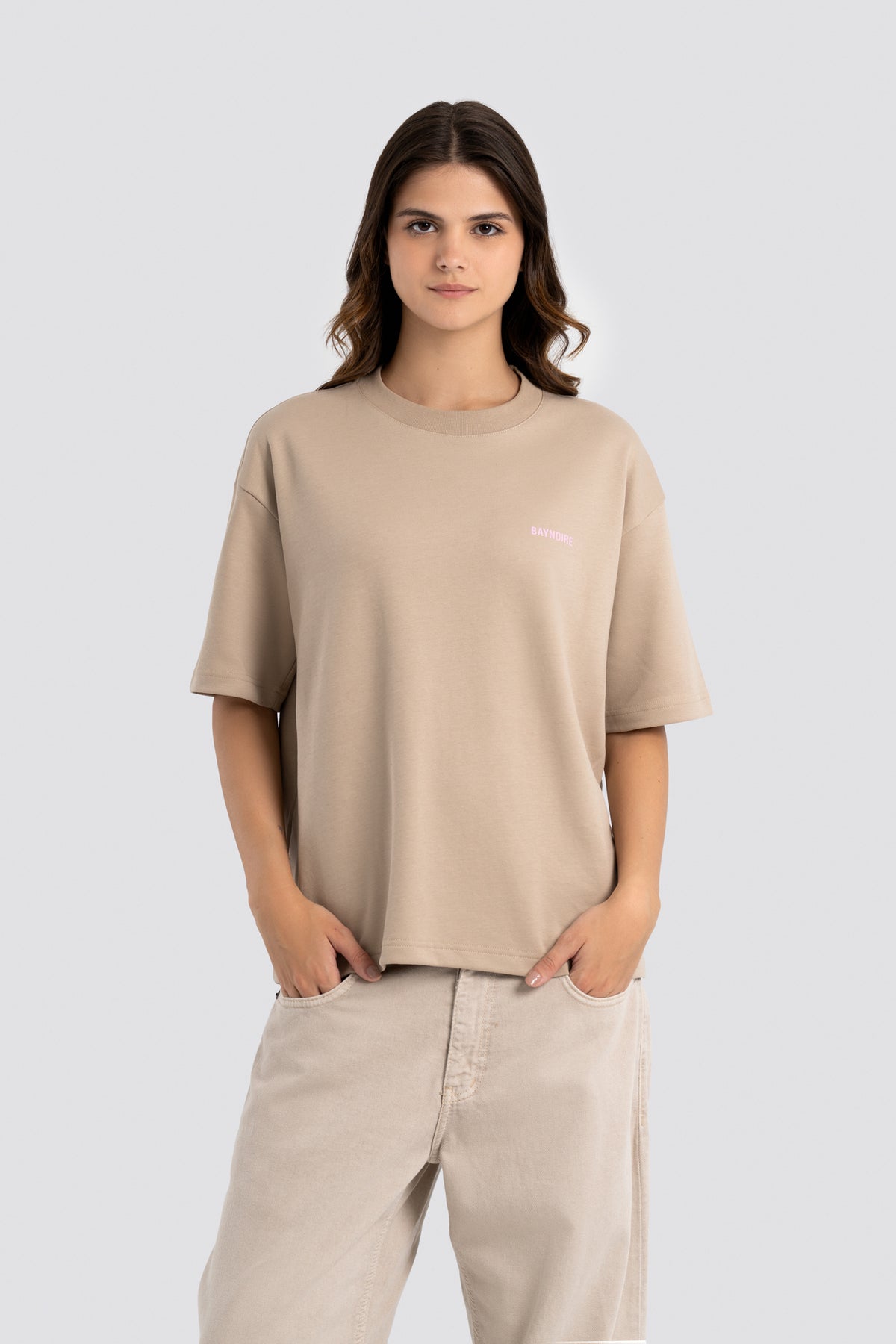 Woman wearing a beige t-shirt and pants on a white background