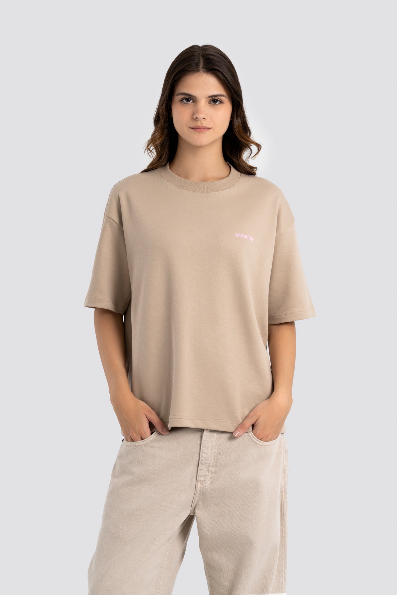 Woman wearing a beige t-shirt and pants on a white background
