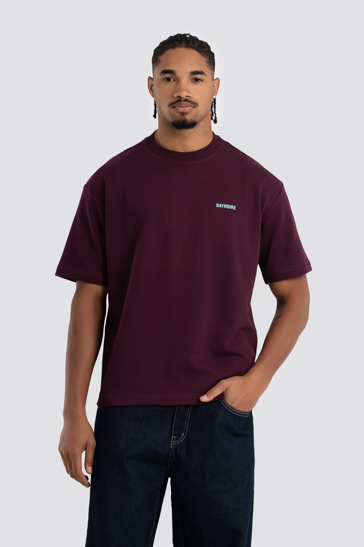 Man wearing a maroon t-shirt with a small logo on a white background