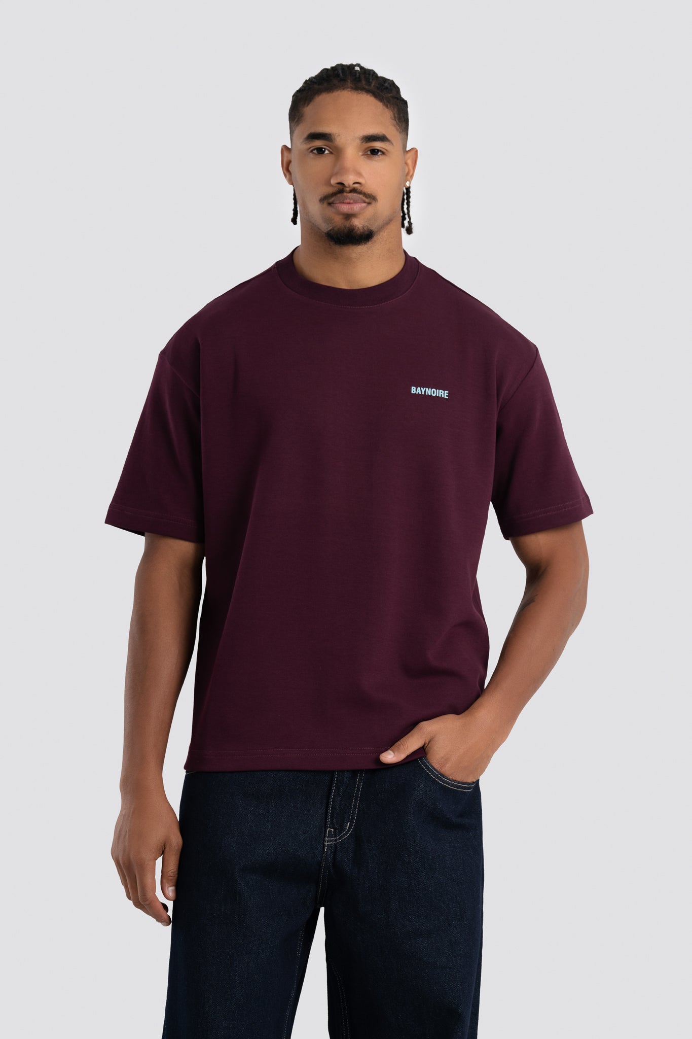Man wearing a maroon t-shirt with a small logo on a white background
