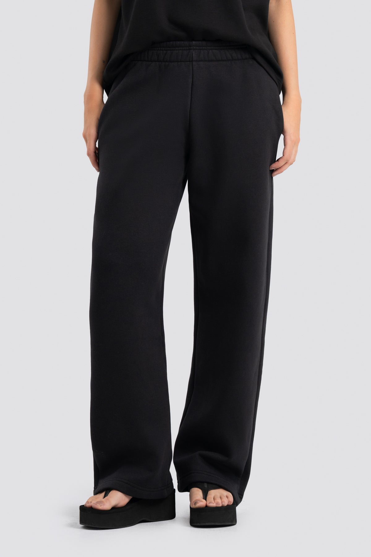 Person wearing black wide-leg pants on a white background