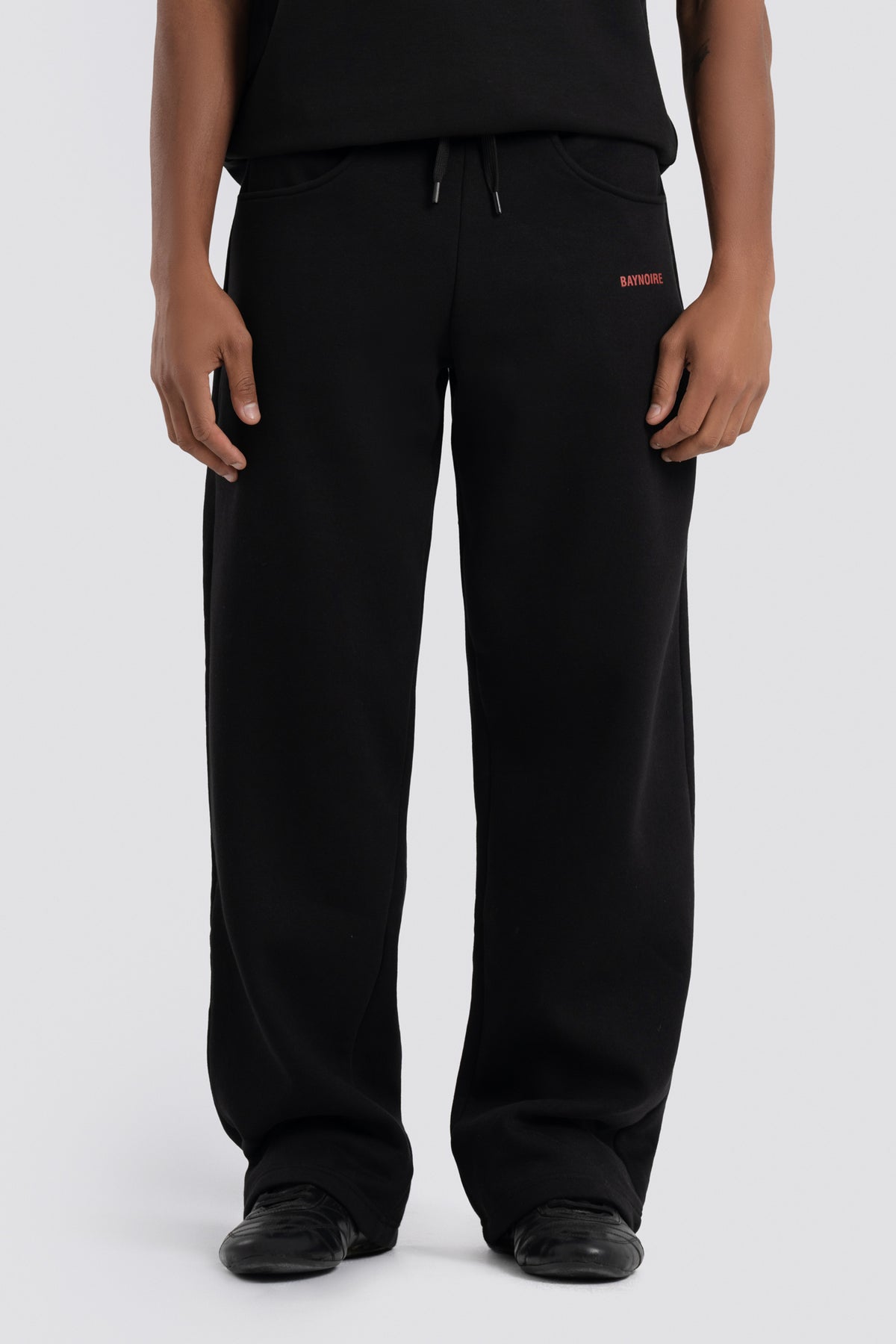 Person wearing black pants with a red logo on a white background
