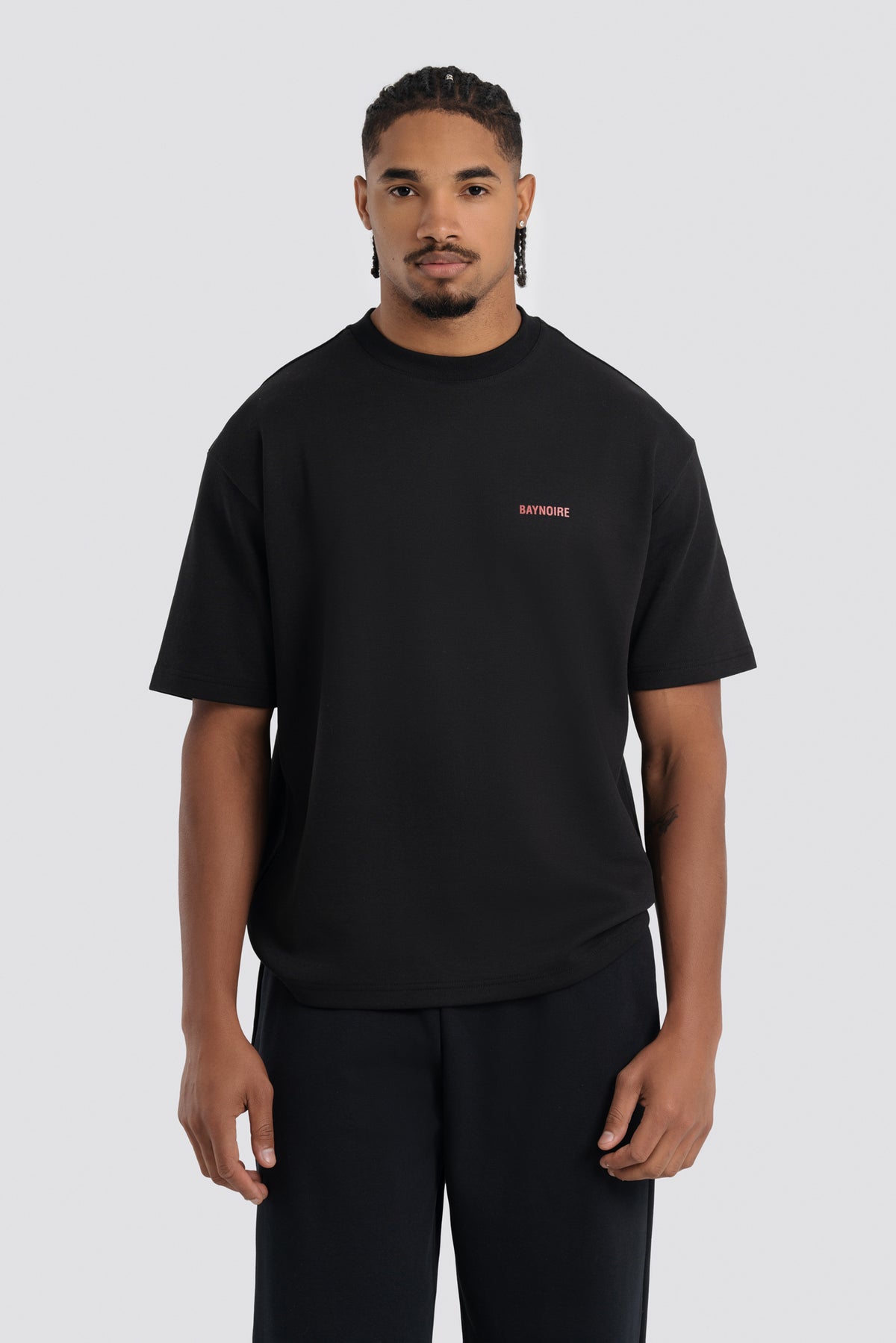 Man wearing a black t-shirt with a small red logo on a white background